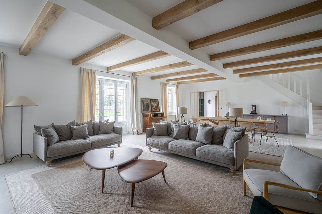 Vue séjour salle à manger esprit campagne moderne avec cheminée ancienne, poutres en bois, buffet bas sur mesure